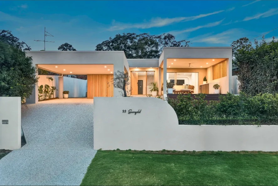 Modern Gold Coast home at dusk with an open timber-lined carport and covered patio